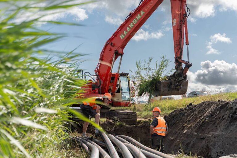 Graafmachine graaft sleuf en grondwerkers zijn aan het werk voor energietransitie door Haarsma Groep bij Oterleek Obdam